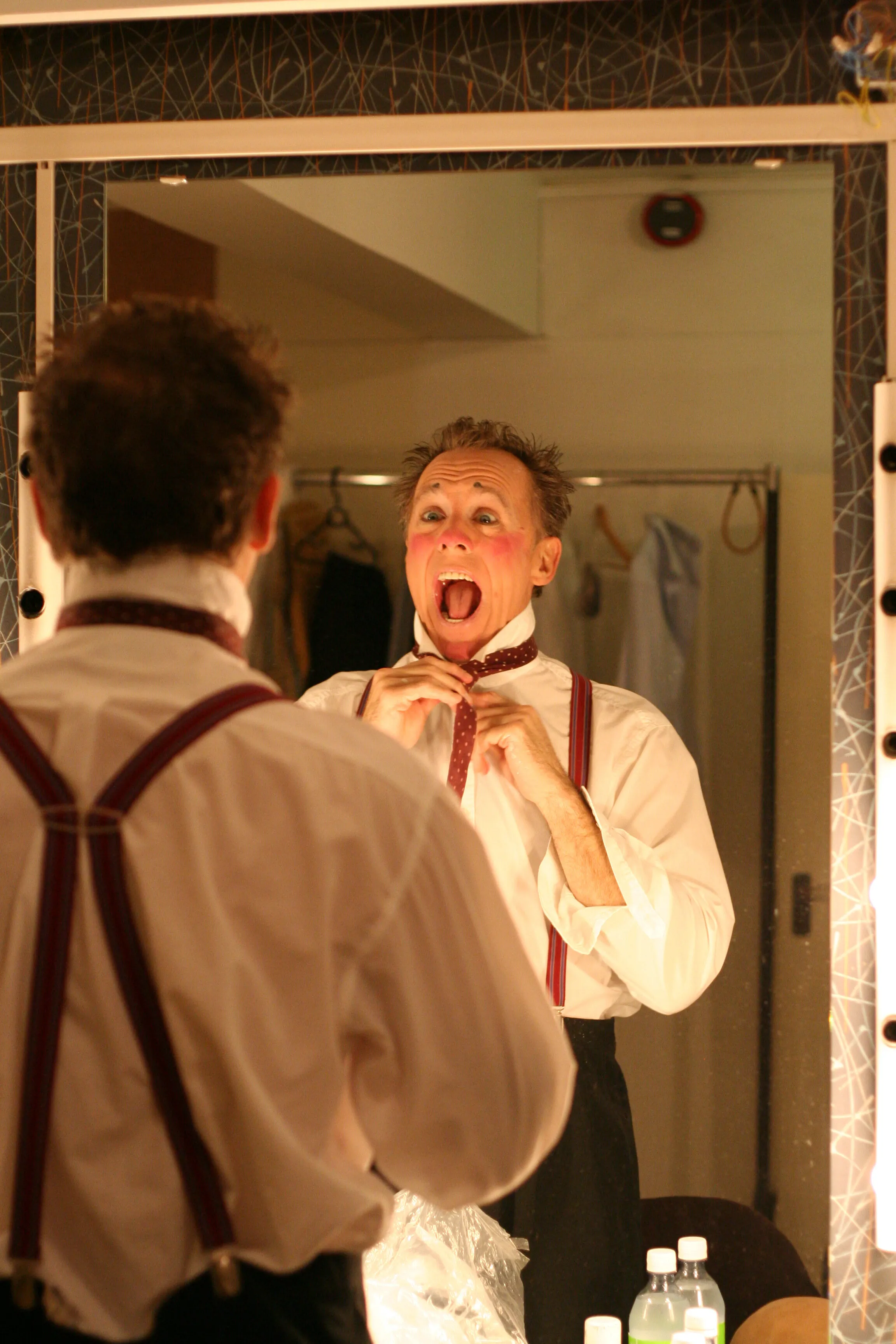 Wolfe Bowart in a dressing-room mirror, adjusting his tie